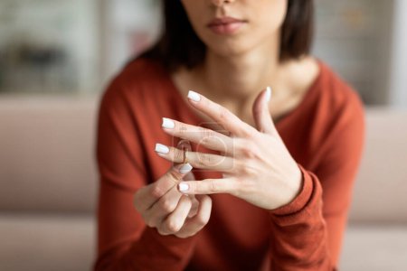 Close-up of a womans hands as she removes her wedding ring, signifying relationship troubles