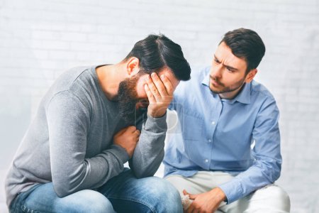 Therapieunterstützung. Gruppenmitglieder trösten weinenden süchtigen Mann bei Reha-Sitzung und drücken Empathie aus
