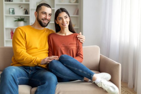 Téléchargez les photos : Couple souriant engageant une conversation sur le canapé, rayonnant de positivité - en image libre de droit