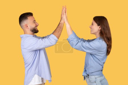 Foto de Imagen enérgica y festiva de un hombre y una mujer dando una alta cinco, simbolizando el éxito y el trabajo en equipo - Imagen libre de derechos