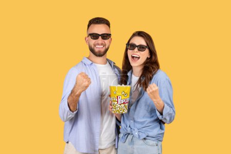 Photo for Smiling man and woman wearing 3D glasses holding popcorn, enjoying a fun moment together - Royalty Free Image