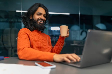Téléchargez les photos : Professionnel souriant ayant un moment agréable tout en interagissant avec son ordinateur à un bureau - en image libre de droit