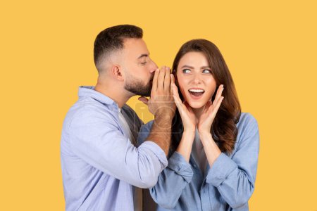 Photo for A man whispers into a womans ear, evoking her surprised and excited reaction - Royalty Free Image