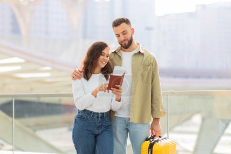 Téléchargez les photos : Un moment intime alors qu'un couple examine ensemble un passeport près d'une balustrade en verre, suggérant une préparation au voyage - en image libre de droit