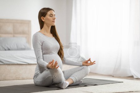 Foto de Mujer embarazada practicando ejercicios de respiración meditativa en el suelo de un dormitorio, encarnando tranquilidad y atención plena - Imagen libre de derechos
