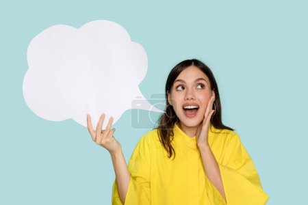 Photo for Happy excited dreamy Latin woman with speech bubble in hand symbolizing power of expression and connection suggests to place your advertising content isolated on blue background - Royalty Free Image