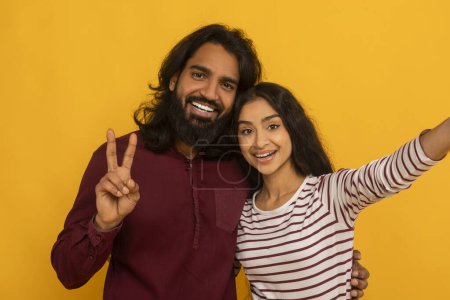 Animiertes Paar macht ein Selfie mit einer Frau, die ein Friedenszeichen blinkt, beide lächeln herzlich auf gelbem Hintergrund