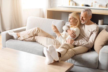 Ein elegantes Paar sitzt gemütlich auf einer modernen Couch und präsentiert einen minimalistischen und doch warmen Wohnraum mit natürlichem Licht