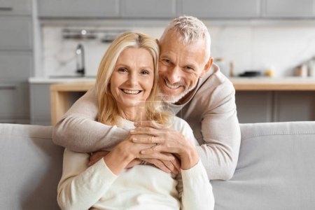 Photo for Happy senior man embracing his partner from behind, both smiling joyfully in a domestic setting - Royalty Free Image