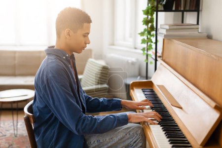 Photo for A serene setting captured as a young musician in casual attire expertly practices on an elegant piano at home - Royalty Free Image