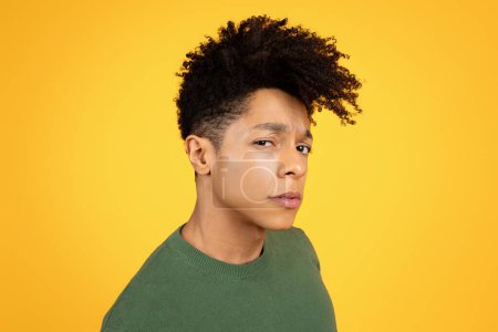 Téléchargez les photos : Portrait en gros plan d'un jeune homme noir avec une expression contemplative sur fond jaune - en image libre de droit