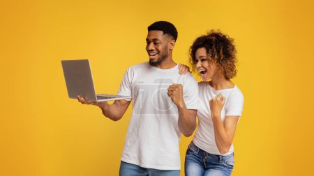 Photo for Great success Amazed african-american girl and guy looking at laptop and enjoying good news, orange background - Royalty Free Image