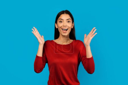 Photo for Surprised Young Woman Raising Hands And Looking At Camera With Excitement, Amazed Millennial Female Emotionally Reacting To Nice Offer Or Promo, Standing Isolated On Blue Background, Copy Space - Royalty Free Image