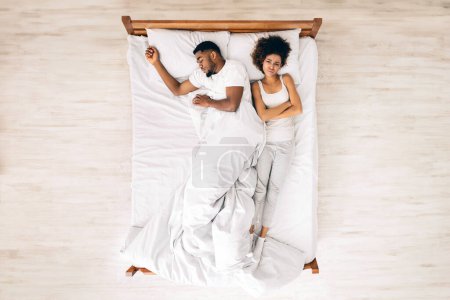 Téléchargez les photos : Femme noire inconfortable dormant par l'homme au lit, vue de dessus avec espace libre - en image libre de droit