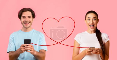 Téléchargez les photos : Un homme en chemise bleue utilise joyeusement son smartphone et une femme en tee-shirt blanc, avec ses cheveux en queue de cheval, regarde avec excitation son téléphone, tous deux liés par un cœur dessinant sur un fond rose vif - en image libre de droit
