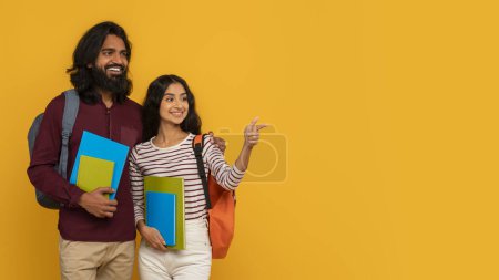 Smiling male and female students with backpacks and colorful notebooks pointing away on a vibrant yellow background