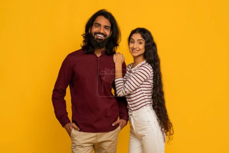 A cheerful man and woman confidently pose with thumbs up, their bright smiles indicating positivity and approval on a yellow background