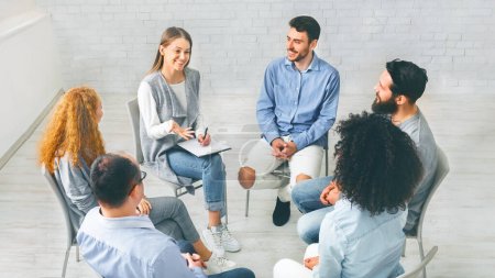 Foto de Grupo de apoyo psicológico. Diversas personas felices sentadas en círculo de confianza en la sesión de terapia, discutiendo su logro en la recuperación - Imagen libre de derechos