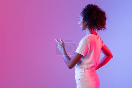 Una figura femenina apunta a la gran pantalla en blanco de un teléfono inteligente de gran tamaño en un entorno iluminado por neón