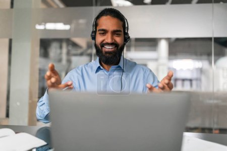 Photo for Man in blue shirt and headset making a friendly gesture while on a video call, representing openness and collaboration - Royalty Free Image