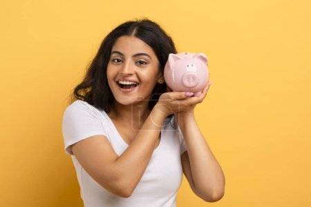 A joyful woman showcasing a piggy bank signifies financial savings, responsibility, and planning