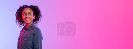 Téléchargez les photos : Charmante dame afro-américaine regardant l'espace libre et souriante, sur un superbe fond dégradé passant du rose au violet, parfaite pour divers thèmes - en image libre de droit