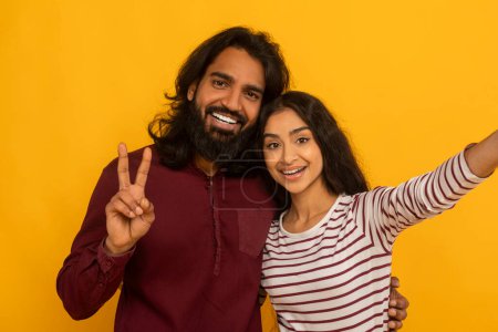 Animiertes Paar macht ein Selfie mit einer Frau, die ein Friedenszeichen blinkt, beide lächeln herzlich auf gelbem Hintergrund