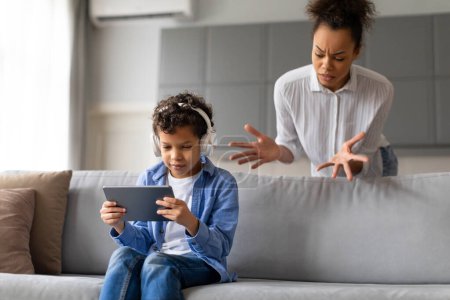 Madre expresando preocupación por el uso de los hijos de la tableta con auriculares