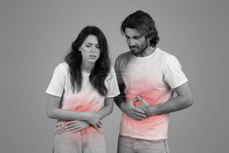 Monochromes Bild von Mann und Frau in weißen T-Shirts, beide mit Händen auf dem Bauch und schmerzverzerrtem Gesichtsausdruck, unterstrichen durch einen Farbtupfer auf dem Oberkörper, der auf Unbehagen oder Krankheit hinweist