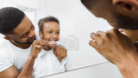 Foto de Cuidar padre cepillarse los dientes hijas pequeñas en el baño - Imagen libre de derechos
