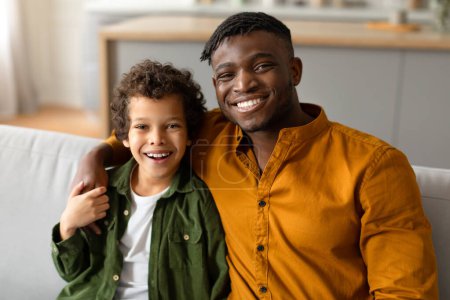 Photo for Father and son share a joyful moment together, smiling and embracing in a warm, home setting - Royalty Free Image
