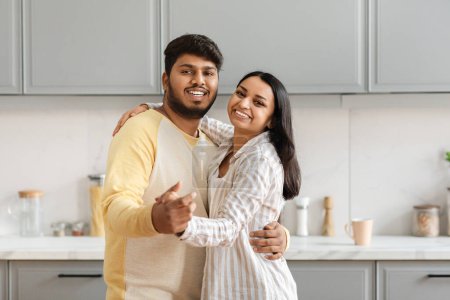 Foto de Amar alegre pareja india joven bailando en acogedor interior de la cocina en casa. Feliz romántico milenario oriental hombre y mujer disfrutando del tiempo juntos, espacio de copia - Imagen libre de derechos