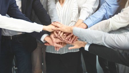 Photo for A group of professionals in suits and casual attire stack their hands in a gesture of unity, teamwork, and partnership - Royalty Free Image
