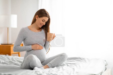Foto de Una mujer joven se ve disfrutando de una cálida taza de té en medio de una cómoda y acogedora habitación - Imagen libre de derechos