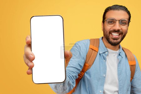 Foto de Involucrar al hombre indio presentando un teléfono inteligente con una pantalla en blanco a la cámara para maquetas - Imagen libre de derechos