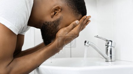 Afroamerikaner in einer täglichen Routine aus Spritzwasser im Gesicht für einen neuen Start in den Tag