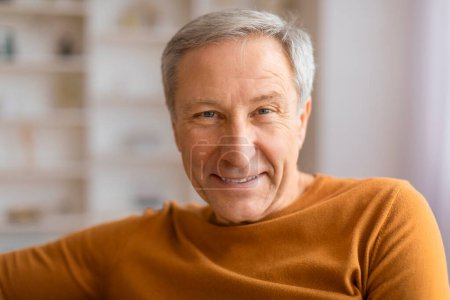 Téléchargez les photos : Gros plan d'un vieil homme joyeux souriant chaleureusement avec un fond d'étagère flou améliorant l'atmosphère intime - en image libre de droit