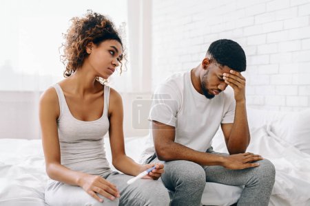Téléchargez les photos : Un jeune couple afro-américain fait face à une déception avec un résultat négatif au test de grossesse dans un cadre domestique - en image libre de droit