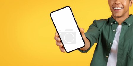 Photo for Cropped of african american man in casual clothes extends a smartphone towards the camera, the screen blank and ready for content - Royalty Free Image