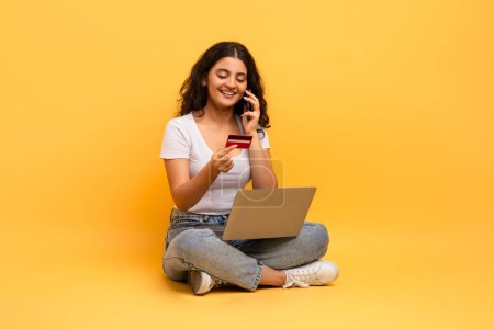 Foto de Una mujer sentada utiliza una tarjeta de crédito con su computadora portátil, mostrando la facilidad del comercio electrónico y las transacciones en línea - Imagen libre de derechos