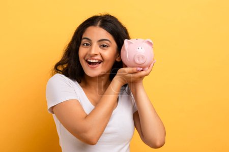 A joyful woman showcasing a piggy bank signifies financial savings, responsibility, and planning