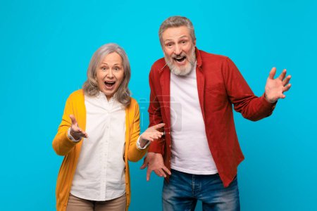Photo for Omg, Amazing Offer. Excited senior man and woman shouting emotionally looking at camera, reacting to surprising news together, standing on blue studio background. Concept of wow deal - Royalty Free Image