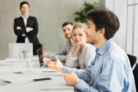 A group of professionals engaged in a discussion with a man gesturing while speaking and others listening attentively