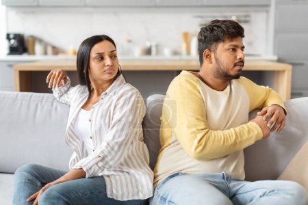 Photo for Indian man and woman sit back to back with troubled expressions, stressed couple indicating a disagreement or upset. - Royalty Free Image