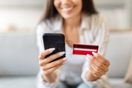 Foto de Recortado de la señora que sostiene una tarjeta de crédito y un teléfono inteligente, significa conveniencia y tecnología en las compras modernas - Imagen libre de derechos