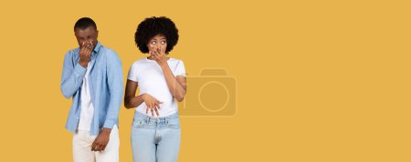 Téléchargez les photos : L'homme et la femme afro-américains se tiennent le nez, faisant des visages de dégoût ou de dégoût dans un contexte jaune - en image libre de droit
