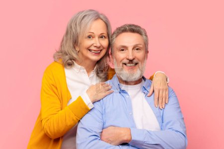 Téléchargez les photos : Mariage à maturité. Joyeux couple de personnes âgées rayonnant de bonheur et de romance, étreignant sur fond de studio rose, souriant à la caméra. Portrait de personnes âgées amoureuses posant ensemble - en image libre de droit