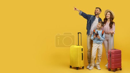 Foto de Una familia con equipaje sonríe y señala hacia un lado, aislada sobre un fondo amarillo, sugiriendo viajes y emoción - Imagen libre de derechos