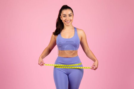 Confident woman illustrating how to measure hips with a tape measure, with focus on technique