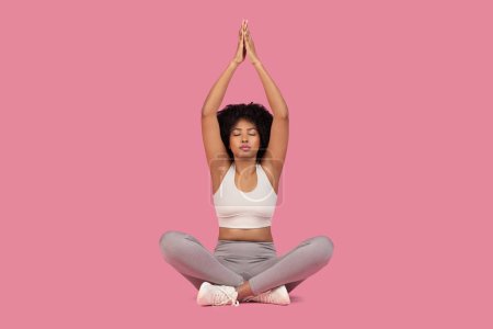 Mujer afroamericana serena demostrando atención plena y tranquilidad en una pose de meditación